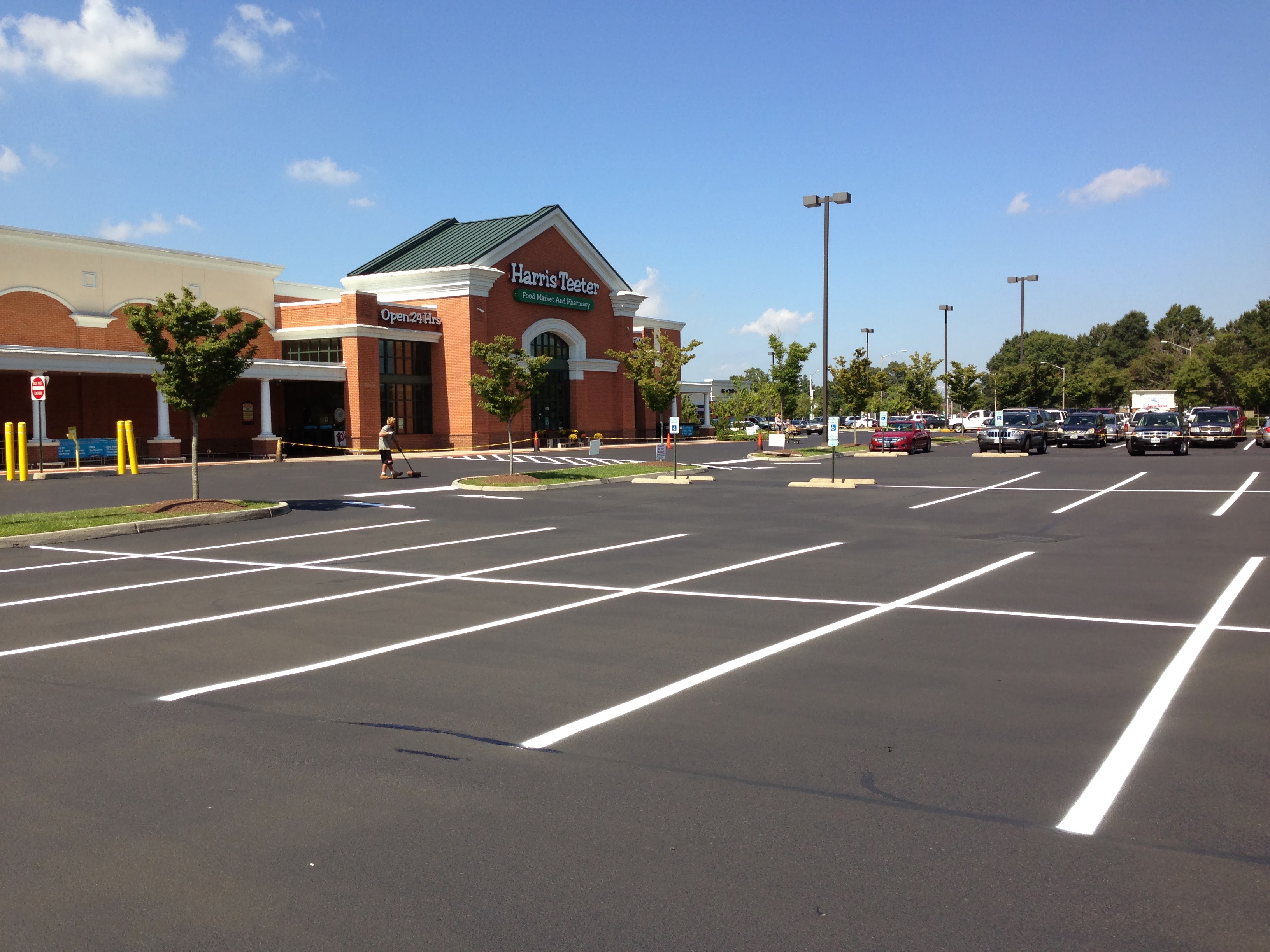 Harris Teeter parking lot freshly sealcoated and striped by J. Worden and Sons, crew sweeping the entrance