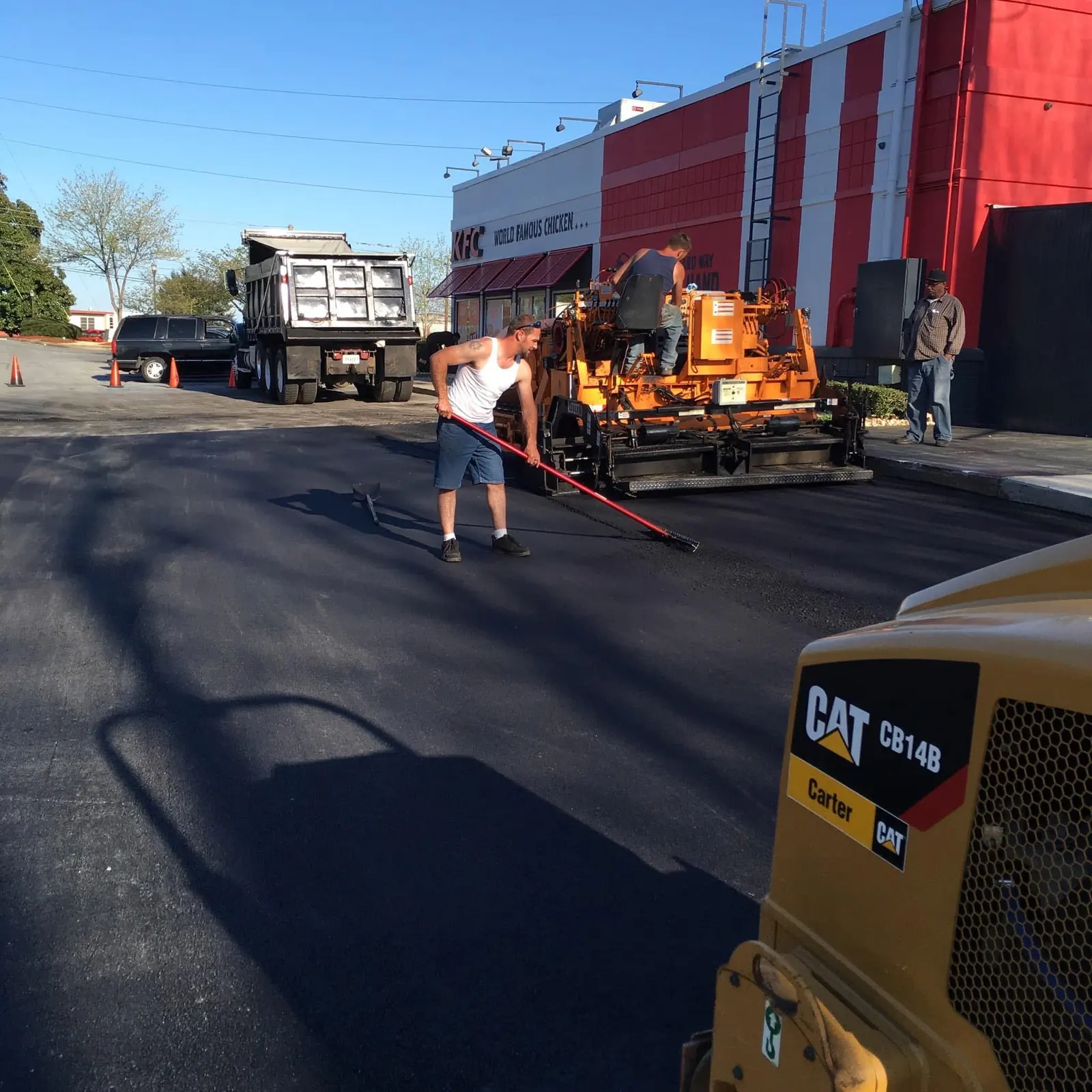 Crew luting fresh mat behind the paver at a KFC